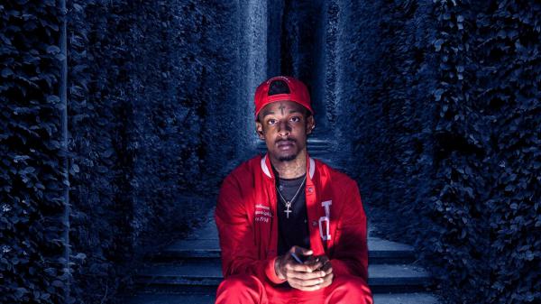 Free 21 savage is sitting on steps between blue leaves wall wearing red dress and cap hd 21 savage wallpaper download