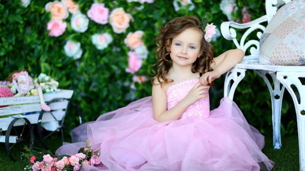 Free ash eyes cute little girl is sitting on green grass wearing pink frock in blur flowers with leaves background hd cute wallpaper download