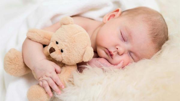 Free baby is sleeping on sandal color textile covered with white towel and hugging teddy doll hd cute wallpaper download