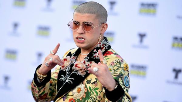 Free bad bunny aesthetic is wearing colorful designed coat having rings in fingers and hanging earring hd music wallpaper download