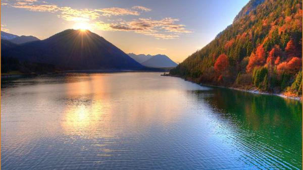 Free calm body of water between orange green trees covered mountains with sunbeam hd macbook wallpaper download