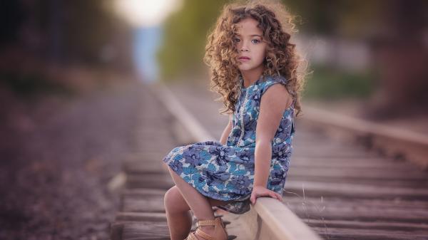 Free curly hair cute little girl is sitting on railroad wearing flower printed dress hd cute wallpaper download