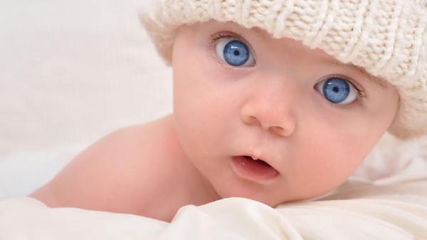 Free cute ash eyes baby is lying down on bed wearing white knit cap 4k hd cute wallpaper download