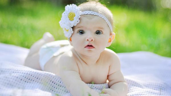 Free cute baby is lying down on a white towel and having a white headband on head hd cute wallpaper download