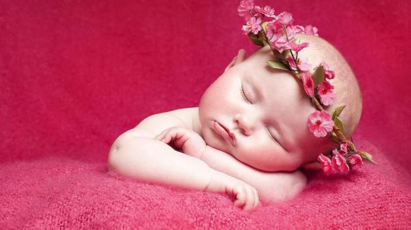 Free cute baby is sleeping on red towel and having flower crown on head in red background hd cute wallpaper download