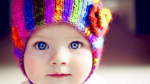 Free cute dark blue eyes baby is wearing colorful knitted wool cap in a blur background hd cute wallpaper download