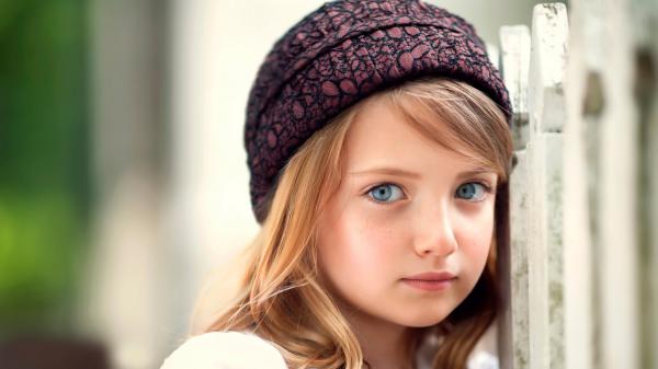 Free cute girl is standing near white gate wearing woolen cap with ash eyes in a blur background hd cute wallpaper download