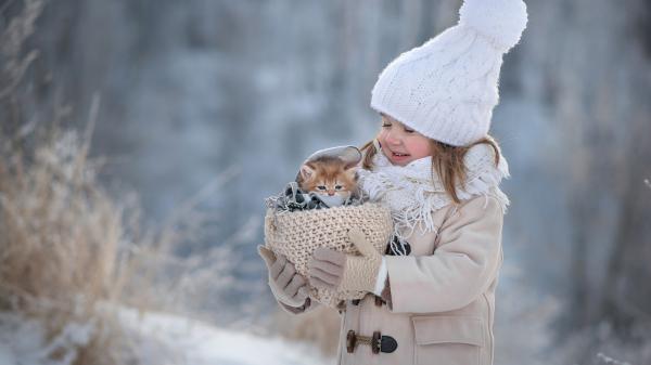 Free cute little girl is holding kitten in woolen basket wearing woolen knitted cap and scarf in show background hd cute wallpaper download