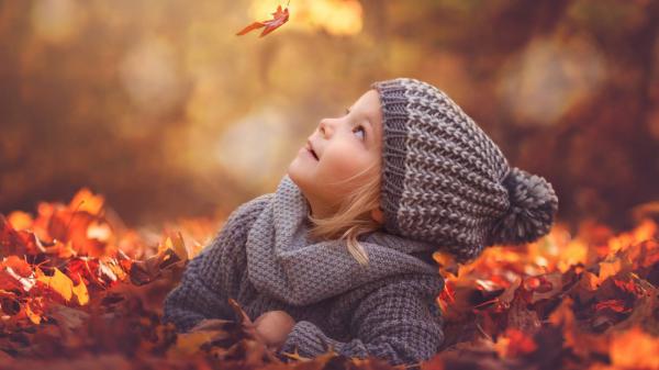 Free cute little girl is lying down on dry leaves looking up flying leaf wearing ash woolen knitted cap and dress hd cute wallpaper download