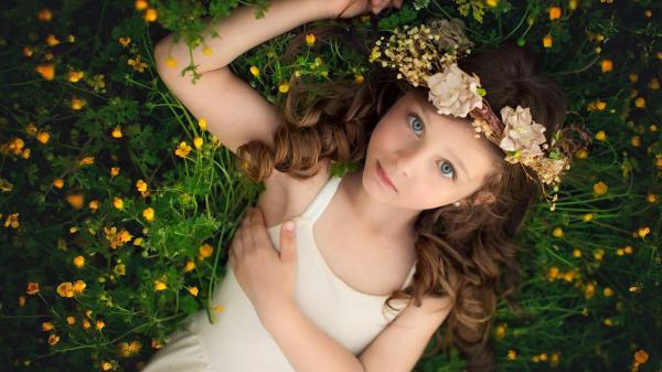 Free cute little girl is lying on yellow flower plant looking up wearing wreath and white dress hd cute wallpaper download