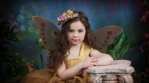 Free cute little girl is placing hand on stone stand wearing golden color dress having wings in back hd cute wallpaper download