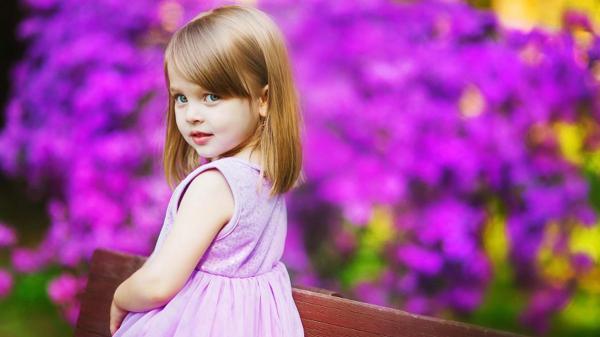 Free cute little girl is standing in dark purple flowers background wearing purple dress looking back hd cute wallpaper download