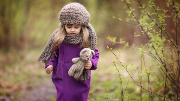 Free cute little girl is wearing purple dress and woolen knitted cap having woolen toy in blur forest background hd cute wallpaper download