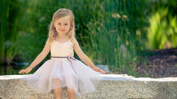 Free cute little girl is wearing white dress sitting on stone pavement in green blur background hd cute wallpaper download