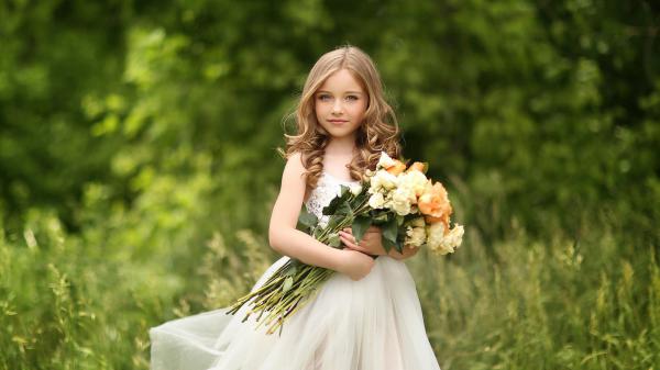 Free cute little girl with flowers is standing on green grass wearing white dress in green blur background hd cute wallpaper download