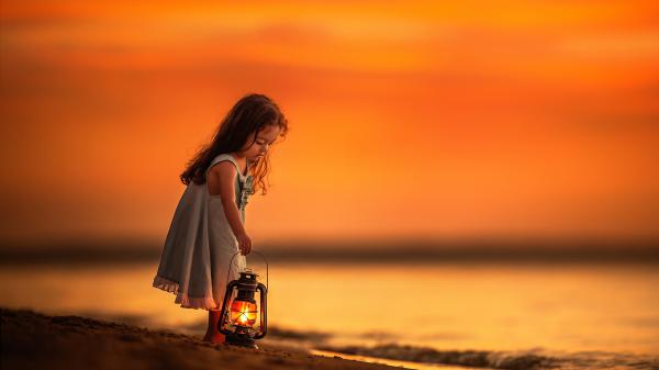 Free cute little girl with lamp standing on beach sand wearing ash dress under orange yellow sky hd cute wallpaper download