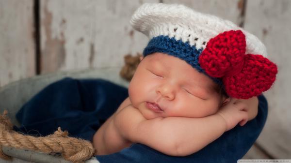 Free cute new born baby is sleeping dark blue satin towel wearing woolen knitted white red cap hd cute wallpaper download