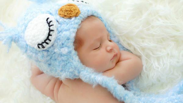 Free cute newborn baby is sleeping on white woolen bed wearing knitted woolen blue cap hd cute wallpaper download