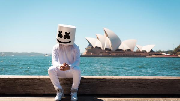 Free dj marshmello is sitting on wood in ocean background wearing white dress hd marshmello wallpaper download