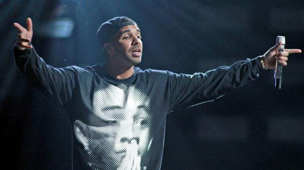 Free drake is wearing black t shirt with face print and cap having mike in hand in blur black background hd drake wallpaper download