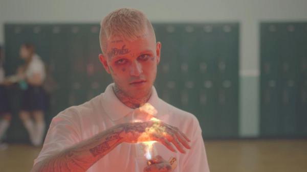 Free lil peep is putting hand on fire with tattoos on face hand neck wearing white tshirt in blur background hd music wallpaper download