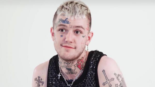 Free lil peep is sitting in white background wearing black tshirt having tattoos on face head neck and hands hd music wallpaper download