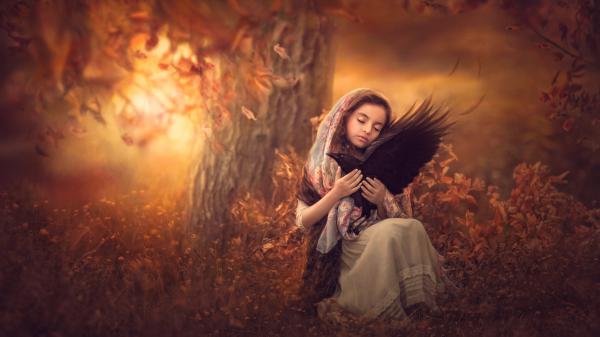 Free little girl is sitting with bird on lap in tree background 4k hd cute wallpaper download