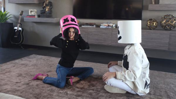 Free marshmello is sitting on floor with selena gomez wearing white dress in tv stand background hd marshmello wallpaper download