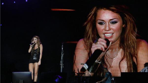 Free miley cyrus is singing on stage with her image on big screen hd miley cyrus wallpaper download