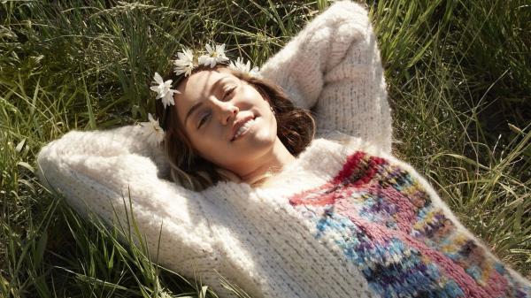 Free miley cyrus with sweater is lying on the grass field hd miley cyrus wallpaper download