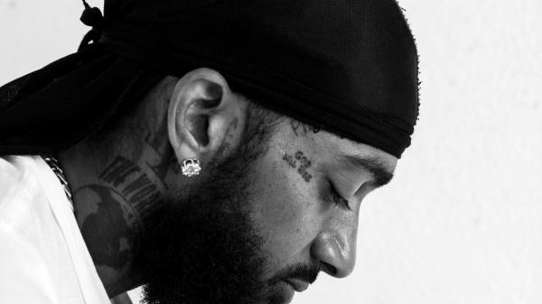 Free nipsey hussle is looking down head covered with black cloth wearing stud in ear hd music wallpaper download