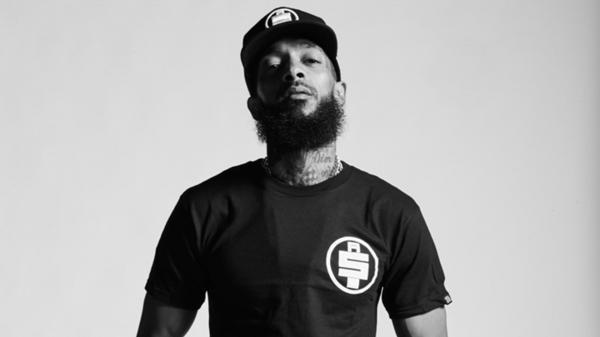 Free nipsey hussle is looking up wearing black tshirt and cap hd music wallpaper download