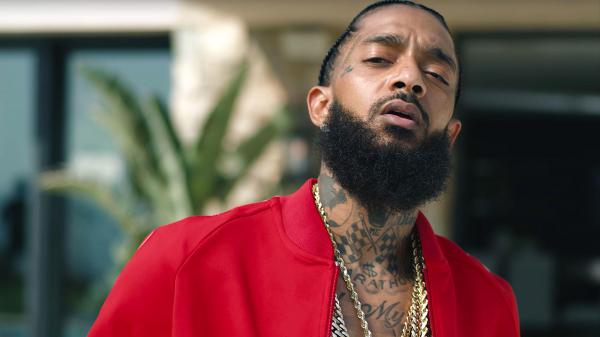 Free nipsey hussle is wearing red coat and having tattoos and chains on neck in a blur background 4k hd music wallpaper download