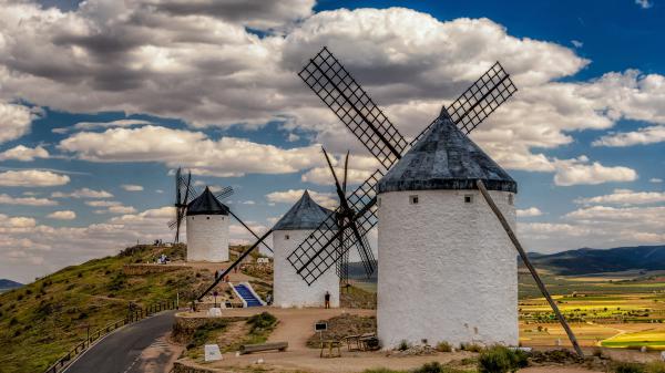 Free people are standing near white windmill under cloudy blue sky hd travel wallpaper download