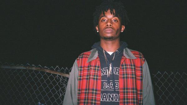 Free playboi carti is wearing red striped coat standing in fence black background wearing gold chains on neck hd music wallpaper download