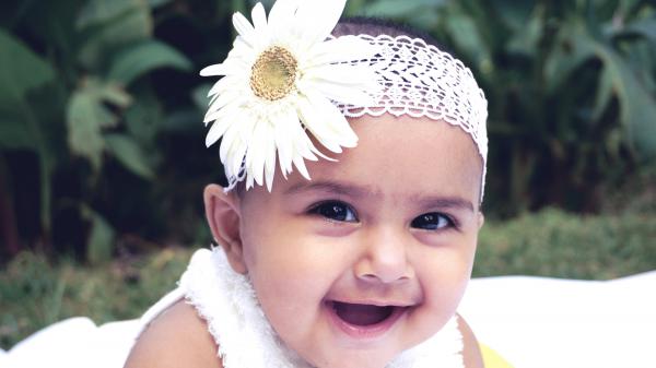 Free smiley cute baby girl is wearing white daisy flower headband lying on white towel in green background 4k hd cute wallpaper download