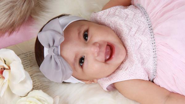 Free smiley cute baby is looking up lying down on floor wearing pink dress and white head band hd cute wallpaper download