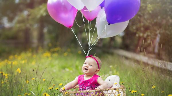 Free smiley cute baby is sitting inside bamboo basket on green grass wearing pink dress with balloons hd cute wallpaper download