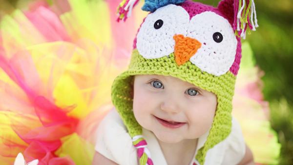 Free smiley cute baby is wearing white dress with colorful wool knitted cap in blur background hd cute wallpaper download