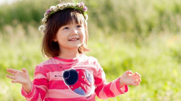 Free smiley cute girl is looking up wearing pink dress with flower crown on head in green blur background hd cute wallpaper download