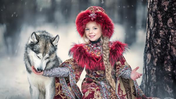 Free smiley little girl is wearing red traditional costume and hat with wolfdog in snow forest background hd cute wallpaper download