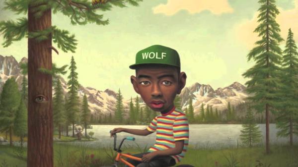 Free tyler the creator comic photo wearing green cap and colorful striped tshirt sitting on bicycle hd music wallpaper download