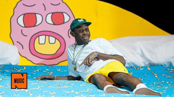 Free tyler the creator is lying on blue bed wearing white tshirt and yellow shorts posing for a photo hd music wallpaper download