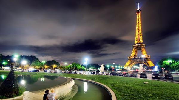 Free yellow lighting paris eiffel tower with shallow background of dark sky and clouds during nighttime hd travel wallpaper download